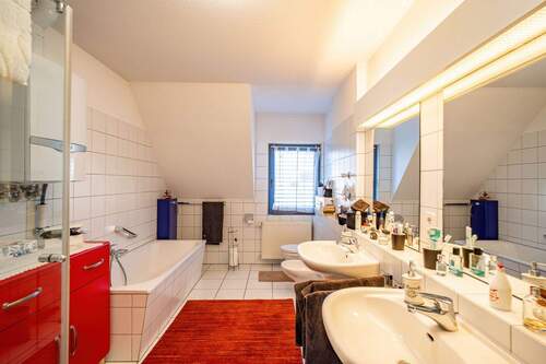 Das Bad ist weiß gefliest und mit Badewanne, Glasdusche und Bidet ausgestattet. - 