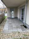 Terrasse mit grauen Steinplatten. Außenherum befinden sich noch zusätzlich Kieselsteine. Ebenso ist die Terrasse über 2 Fenstertüren zu erreichen. - 