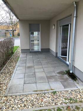 Terrasse mit grauen Steinplatten. Außenherum befinden sich noch zusätzlich Kieselsteine. Ebenso ist die Terrasse über 2 Fenstertüren zu erreichen. - 