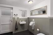 Gäste-WC mit Waschbecken, WC und Urinal sowie direktem Zugang zur Terrasse bzw. zum Garten. - 