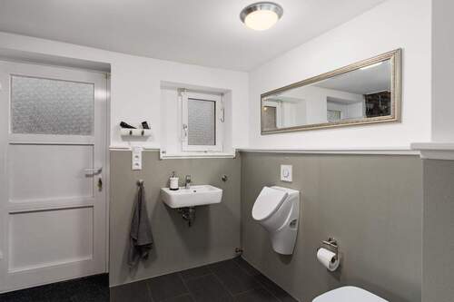 Gäste-WC mit Waschbecken, WC und Urinal sowie direktem Zugang zur Terrasse bzw. zum Garten. - 
