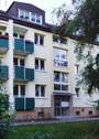Eingangsbereich des mehrstöckigen Wohngebäudes umgeben von Grünanlagen mit Bäumen - SINGLEWOHNUNG im Dachgeschoss sucht Nachmieter!