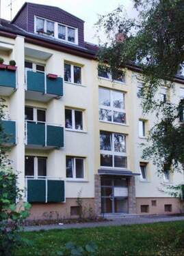 Eingangsbereich des mehrstöckigen Wohngebäudes umgeben von Grünanlagen mit Bäumen - SINGLEWOHNUNG im Dachgeschoss sucht Nachmieter!