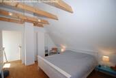 Dachgeschoss-Schlafzimmer mit Holzbalkendecke und Ankleidebereich - 