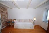 Helles Schlafzimmer mit Dachbalken und großflächigen Fenstern - 