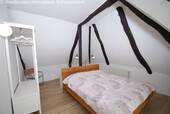 Dachgeschoss-Schlafzimmer mit rustikalen Balken und Spiegelschrank - 
