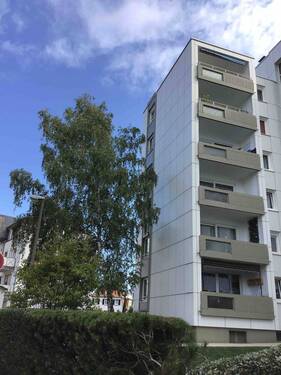 Ansicht des mehrstöckigen Wohngebäudes umgeben von Bäumen - Nachmieter für toll geschnittene 3-Zimmerwohnung gesucht!