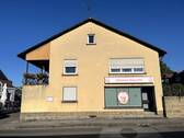 Westansicht mit Ladenzugang und Loggia im Obergeschoss - 5 Zimmer Mehrfamilienhaus, Wohnhaus in Sand