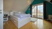 Das zweite Schlafzimmer im Dachgeschoss bietet direkten Zugang zum überdachten Balkon - 