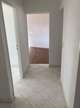 Flur mit weiß angelegten Wänden und grau-weißen Bodenfliesen - Etagenwohnung mit 62,20 m&sup2; in Heppenheim zur Miete