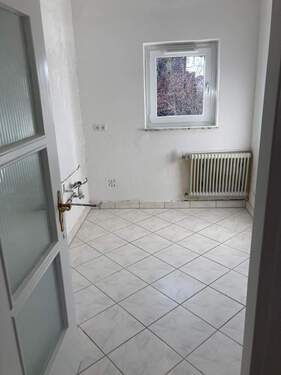 Küche mit weiß angelegten Wänden und weiß-grauen Bodenfliesen - 