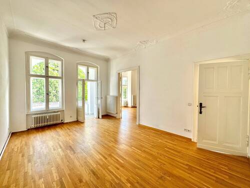 Wohnzimmer mit Stuckdetails und Loggia​ - 5 Zimmer Etagenwohnung zum Kaufen in Berlin