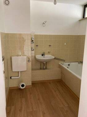 Badezimmer mit gelben Wandfliesen, Badewanne,WC, Waschbecken und Design-Vinylboden. - 