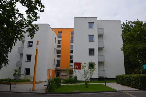Birkenallee 67, Außenansicht auf den barrierfreien Eingangsbereich eines mehrgeschossigen Wohngebäudes mit heller Fassade und sonnengelben Farbakzenten - Kleine 3-Zimmerwohnung in energetisch modernisiertem Gebäude am Baunsberg