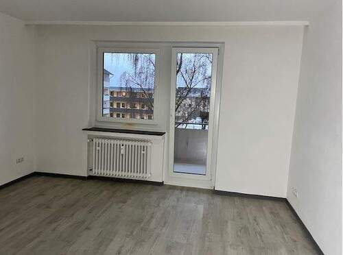 Schlafraum mit hellen Wänden, hellem Bodenbelag in Holzoptik und Zugang zum Balkon.JPG - Etagenwohnung mit 70,50 m&sup2; in Baunatal zur Miete