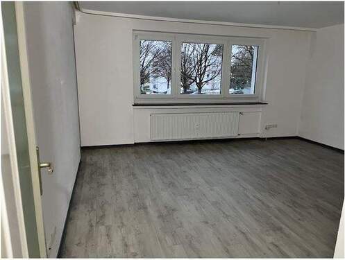 Wohn- und Essbereich mit seitlichem Zugang zum Balkon, helle Wände und heller Bodenbelag in Holzoptik.JPG - 