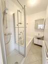 Hell gefliestes Bad mit Wanne und Dusche - 