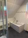 Bad mit Badewanne, Dusche und Fenster im Dachgeschoss - 