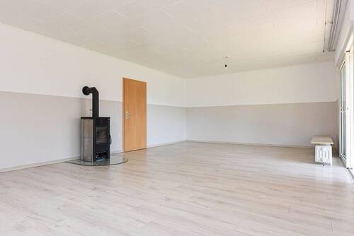Wohnzimmer mit Kamin und Zugang zur teilüberdachten Terrasse - 