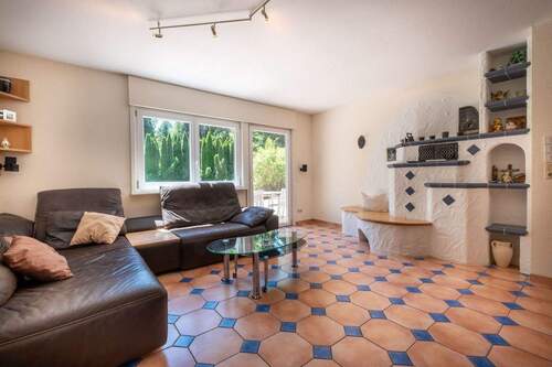 Wohnzimmer mit Kachelofen und Zugang zur Terrasse - 