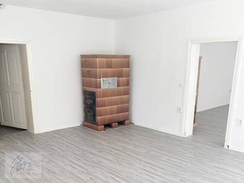 Wohnzimmer mit Kachelofen und Blick Richtung Schlafzimmer - 2 Zimmer Etagenwohnung zur Miete in Mühlberg