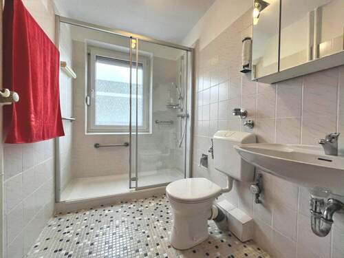 Die fast bodengleiche Dusche wird mit einer Schiebetür geschlossen - 