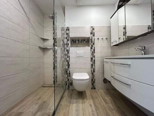 Die nahezu bodengleiche Dusche ist in die Ecke gebaut und kommt ohne Tür aus - 