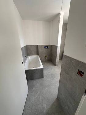 Badezimmer mit Badewanne, Dusche und Fenster - 