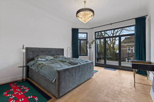 Hauptschlafzimmer mit großer Fensterfront und Balkon - 