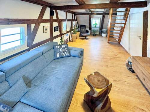 Schönes Wohnzimmer mit Fachwerkelementen und Zugang ins Dachgeschoss - Historisch & saniert: Charmante Dachgeschoss-Maisonette im denkmalgeschützten Fachwerkhaus