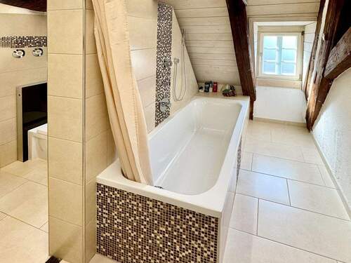 Schöne Aufteilung im hell gefliesten Tageslichtbad mit Badewanne, Waschtisch und WC - 