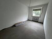 Blick in Schlafzimmer mit grauem PVC-Boden und weißen Wänden mit einem weißen Fenster - 