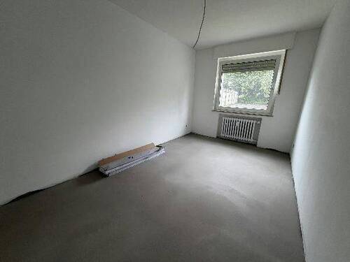 Blick in Schlafzimmer mit grauem PVC-Boden und weißen Wänden mit einem weißen Fenster - 