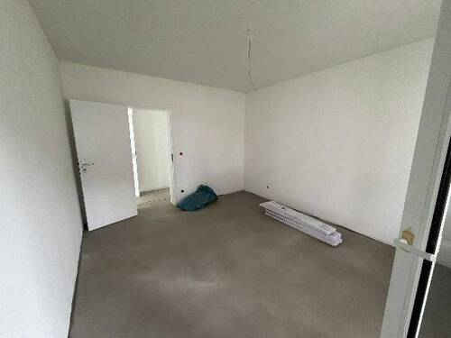 Blick in Wohnzimmer mit grauem PVC-Boden in Laminatoptik und weißen Wänden mit weißen Fenstern - 