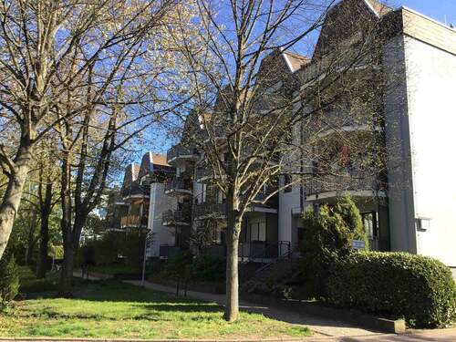 Eingangsbereich des mehrstöckigen Wohngebäudes umgeben von Grünanlagen mit Bäumen und Sträuchern - Tolle 3-Zimmerwohnung in zentraler aber ruhiger Lage sucht Nachmieter!