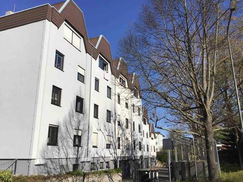 Rückansicht des mehrstöckigen Wohngebäudes umgeben von Grünanlagen mit Bäumen und Sträuchern - 3 Zimmer Etagenwohnung zur Miete in Frankfurt am Main