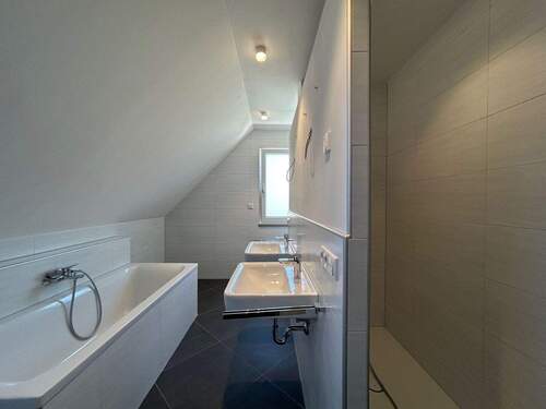 Badezimmer mit großer bodentiefer Dusche, Badewanne, WC und zwei Waschbecken - 