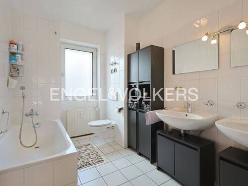 Hell gefliestes Tageslichtbadezimmer mit Badewanne, Doppelwaschbecken und WC - 