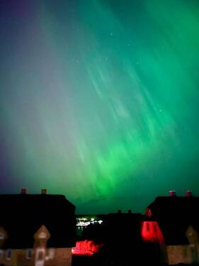 Polarlichter über den reetgedeckten Nachbarhäusern und dem Bootssteg in der Marina, Ansicht II - 