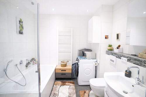 Badezimmer mit ebenerdige Dusche, Badewanne, Waschbecken, Toilette und Waschmaschinenanschluß - 