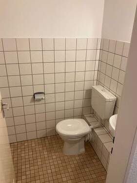 Gäste-WC mit beigen Bodenfliesen und weißen Wandfliesen - 