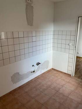 Küche mit beigen Bodenfliesen und weißen Wandfliesen - 