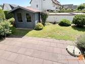 Blick auf die Terrasse und das neuwertige Gartenhaus - 