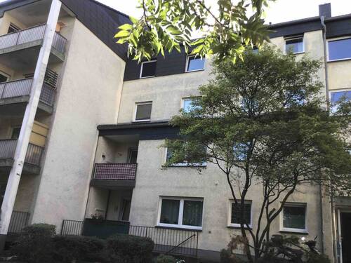 Rückansicht des mehrstöckigen Wohngebäudes mit Loggien, umgeben von Grünanlagen mit Bäumen und grünen Sträuchern - Renovierte Single-Wohnung in Friedrichsdorf sucht neue Mieter!