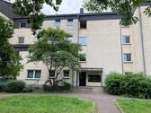 Eingangsbereich des mehrstöckigen Wohnhauses umgeben von Grünanlagen mit Bäumen - Etagenwohnung mit 44,70 m² in Friedrichsdorf zur Miete