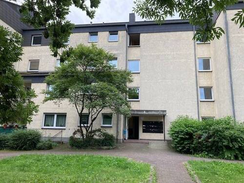 Eingangsbereich des mehrstöckigen Wohnhauses umgeben von Grünanlagen mit Bäumen - Etagenwohnung mit 44,70 m² in Friedrichsdorf zur Miete