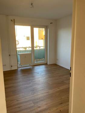 Wohnzimmer mit braunem Vinylboden. Decken und Wände weiß angelegt. Mit Zugang zum Balkon. - Etagenwohnung mit 59,50 m&sup2; in Ginsheim-Gustavsburg zur Miete