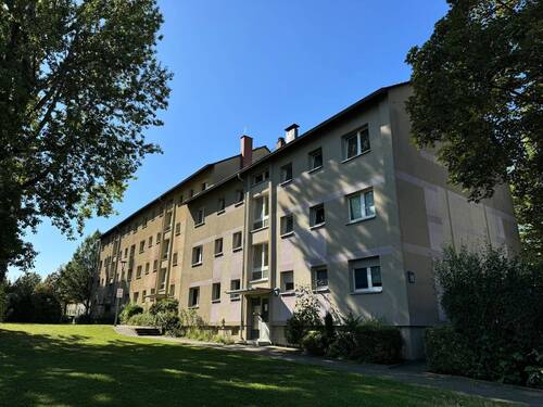 Gebäude Vorderseite des mehrstöckigen Wohnhauses umgeben von Grünanlagen mit Bäumen und Sträuchern - 