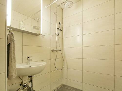 Hell gefliestes Badezimmer mit bodengleicher Dusche und WC - 