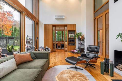 Lichtdurchfluteter Wohnbereich mit einem Sofa auf der linken Seite und einem bewuemen Sessel auf der rechten Seite - 7 Zimmer Einfamilienhaus in Groß Glienicke